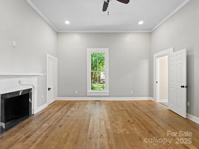 an empty room with wooden floor a fireplace and windows