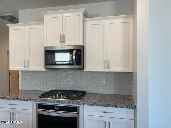 a kitchen with granite countertop white cabinets and stainless steel appliances