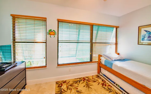 an empty room with chandelier fan and windows