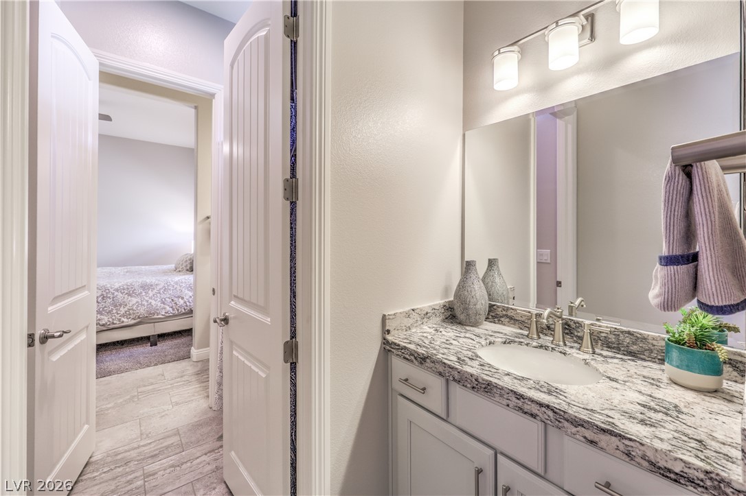 7119 Arabian Ridge Street Las Vegas, NV 89131 - Photo 35 of 73 Luxurious bathroom vanity with a granite countertop, elegant lighting, and ample storage.