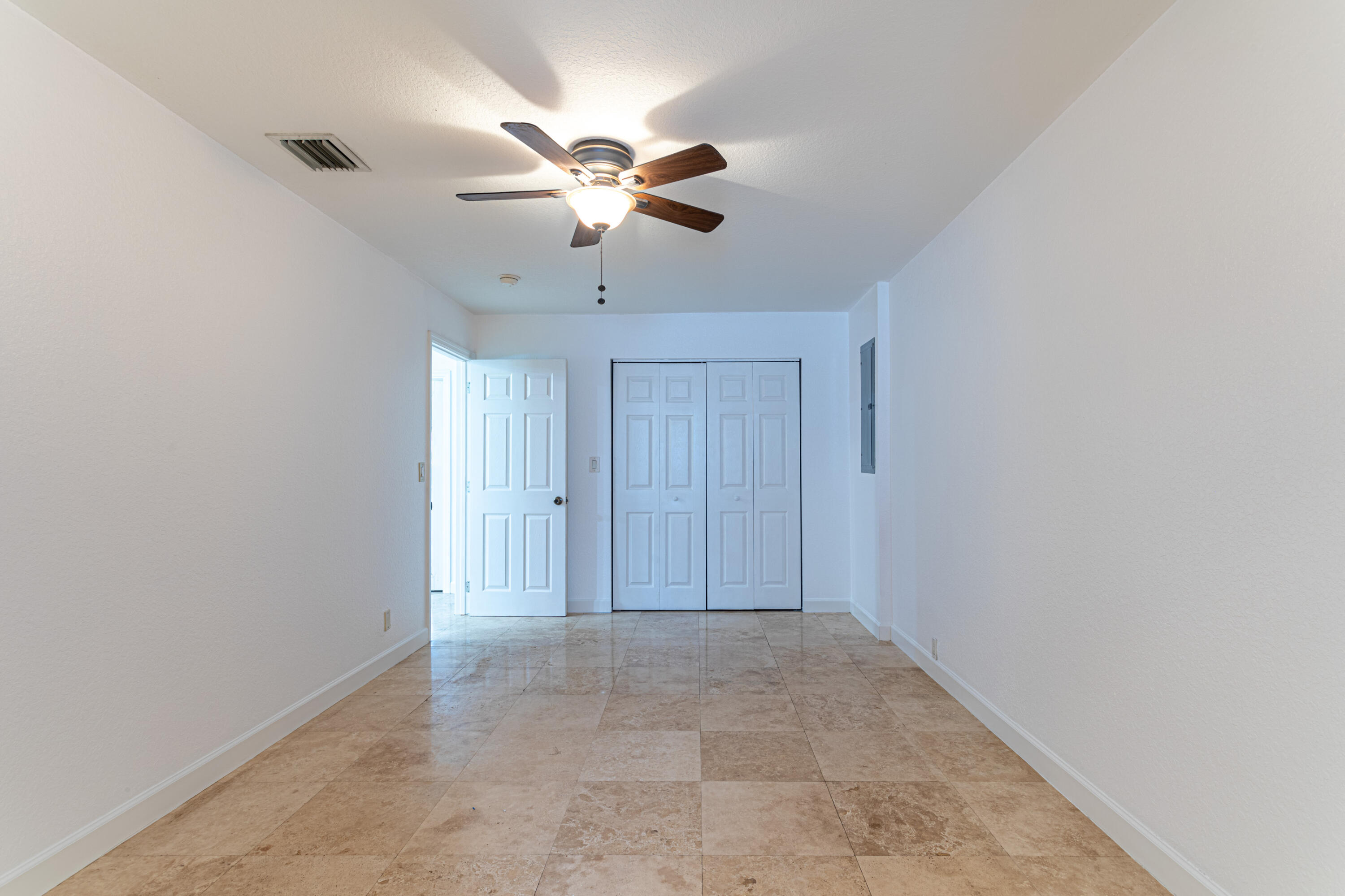 4661 Poseidon Place Lake Worth, FL 33463 - Photo 28 of 36 an empty room with a chandelier fan and windows