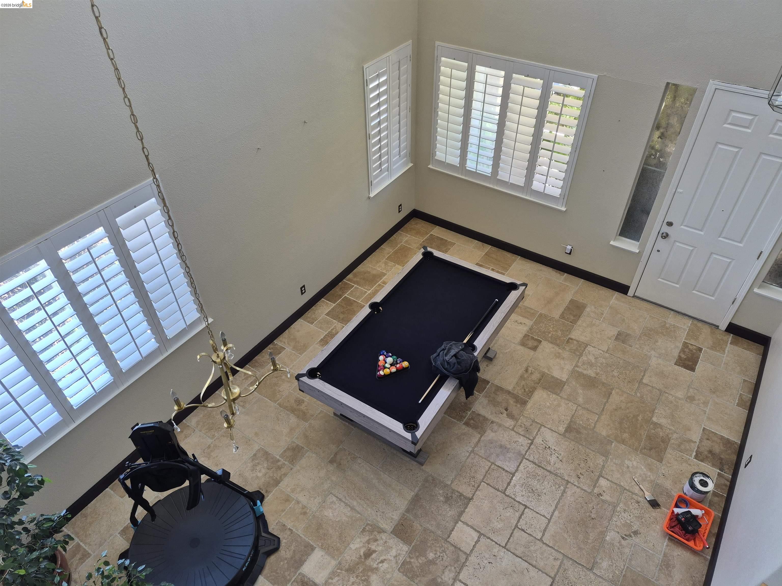 149 Oakpoint Court Bay Point, CA 94565 - Photo 6 of 22 Spacious room featuring high ceilings, light-toned wall paint, large windows with plantation shutters, a white entry door with frosted sidelight, and extensive stone tile flooring