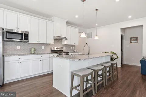 a open kitchen with stainless steel appliances granite countertop a stove a sink a microwave a center island and furniture