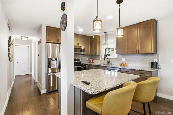 a kitchen with stainless steel appliances granite countertop a sink a refrigerator and a wooden floor