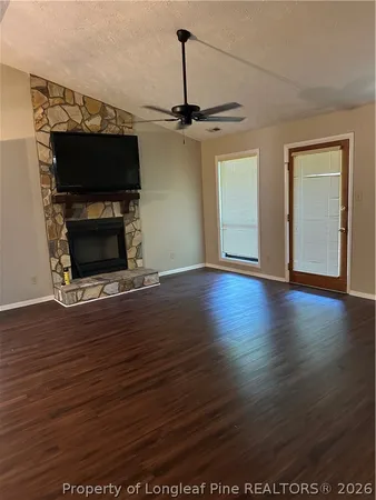 an empty room with wooden floor a fireplace and a window