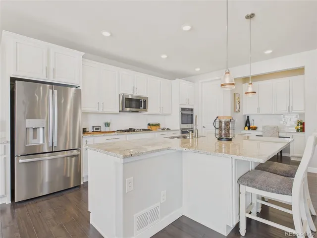 a kitchen with a refrigerator a sink and a stove top oven with wooden floor