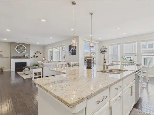a kitchen with stainless steel appliances granite countertop a sink dishwasher and white cabinets with wooden floor