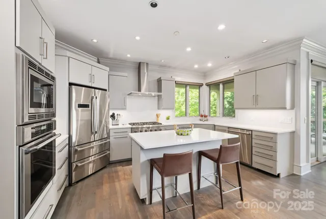 a kitchen with stainless steel appliances a refrigerator a stove a sink and white cabinets