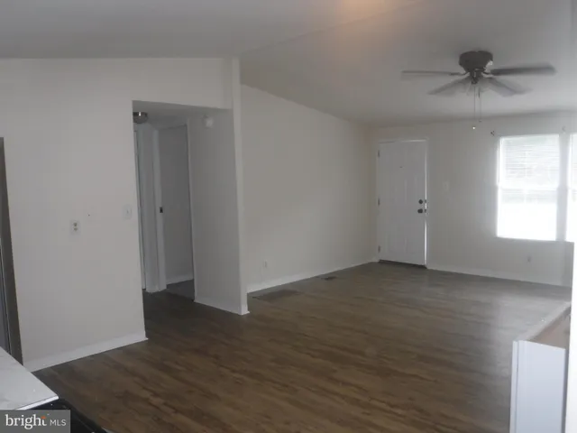 an empty room with wooden floor closet and windows