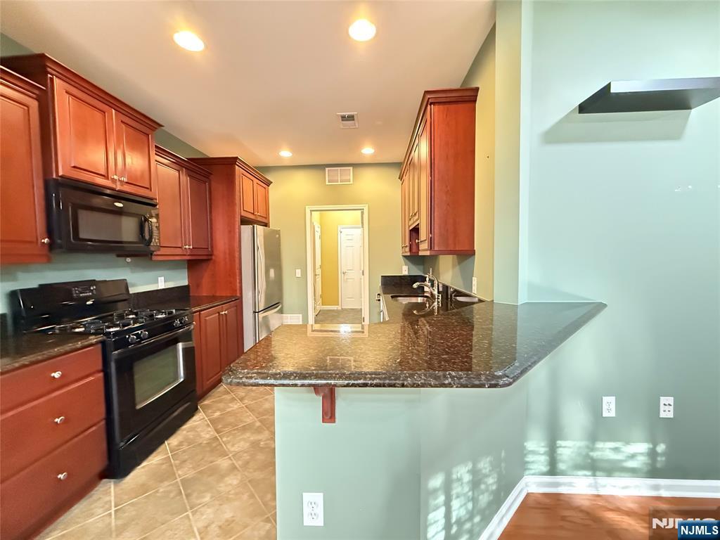 401 River Place Butler, NJ 07405 - Photo 12 of 42 a kitchen with stainless steel appliances granite countertop a stove a sink and a microwave