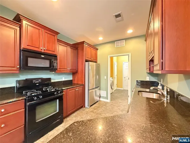 a kitchen with stainless steel appliances granite countertop a stove a sink and a microwave