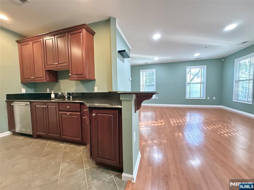 401 River Place Butler, NJ 07405 - Photo 15 of 42 a kitchen with granite countertop wooden cabinets a sink and dishwasher with wooden floor
