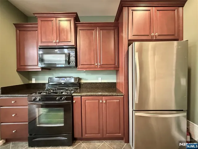 a kitchen with granite countertop a refrigerator stove and microwave