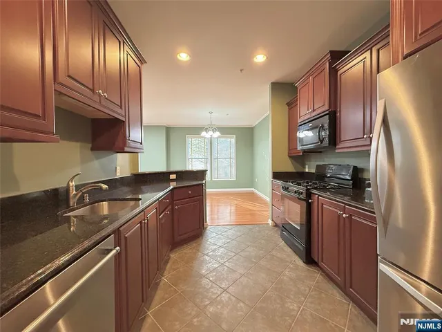 a large kitchen with stainless steel appliances granite countertop a stove refrigerator and cabinets