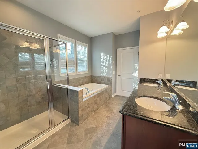 a bathroom with a granite countertop tub sink shower and mirror