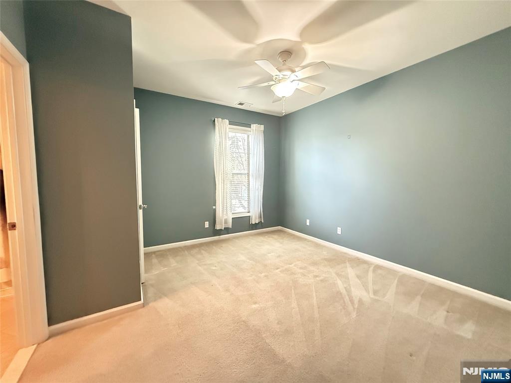 401 River Place Butler, NJ 07405 - Photo 33 of 42 an empty room with a chandelier fan and windows