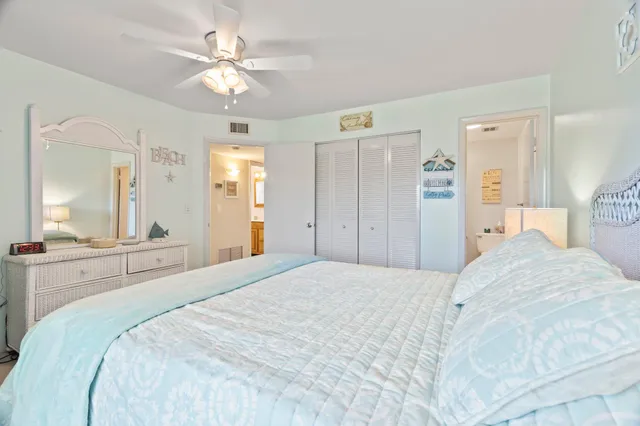 a spacious bedroom with a large bed and chandelier fan