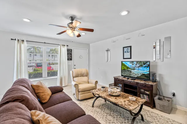 a living room with furniture a ceiling fan and a rug