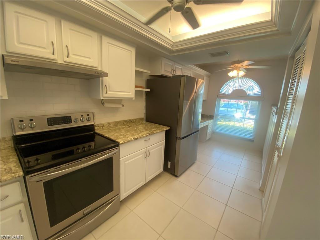 705 Augusta Boulevard, Unit 7055 Naples, FL 34113 - Photo 2 of 18 a kitchen with granite countertop a stove and a refrigerator