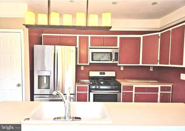 a kitchen with stainless steel appliances kitchen island granite countertop a refrigerator and a stove top oven