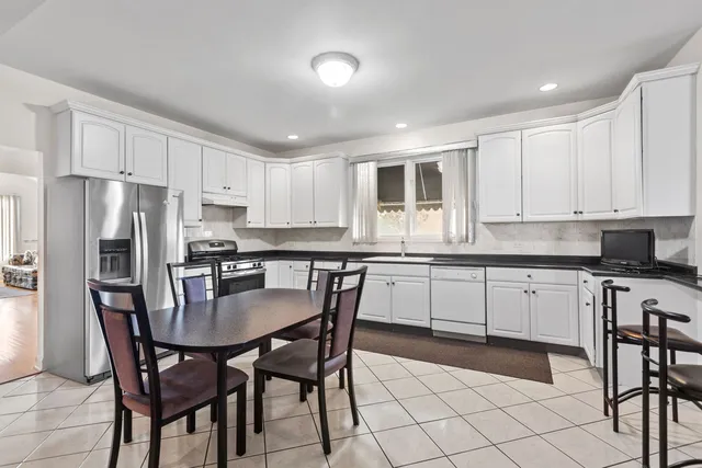 a kitchen with stainless steel appliances granite countertop a dining table chairs refrigerator a sink and dishwasher