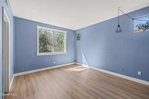 a view of an empty room with window and wooden floor