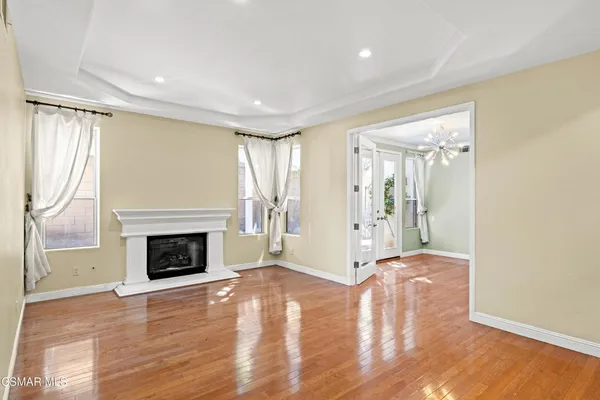 a view of an empty room with wooden floor fireplace and a window
