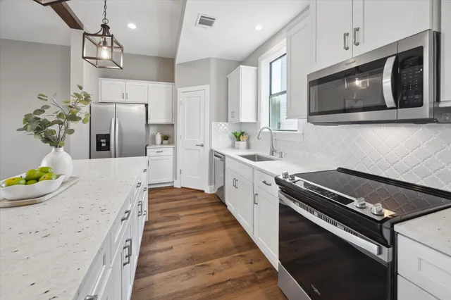 a large white kitchen with a large window and stainless steel appliances