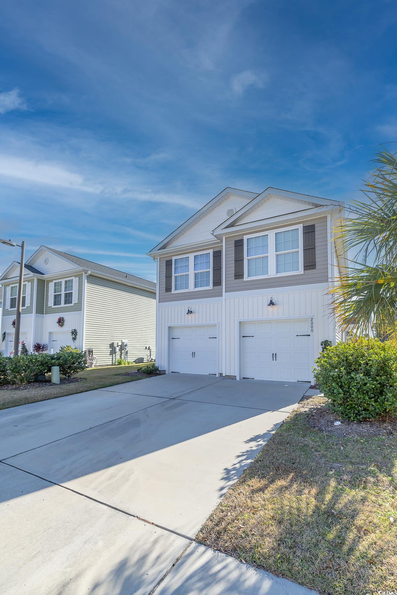 View of front of home featuring board and batten siding, driveway, and an attached garage