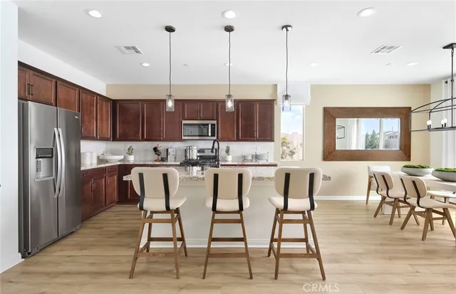 a kitchen with stainless steel appliances kitchen island granite countertop a refrigerator a stove a kitchen island with a dining table and chairs