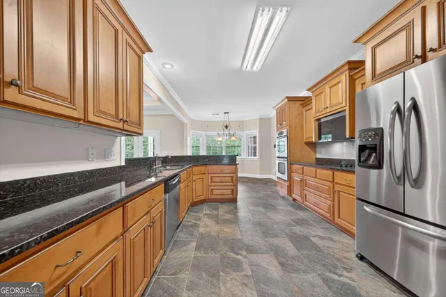 a kitchen with stainless steel appliances granite countertop a refrigerator a stove and a sink