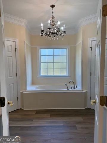 a view of a spacious bathroom with a tub and chandelier