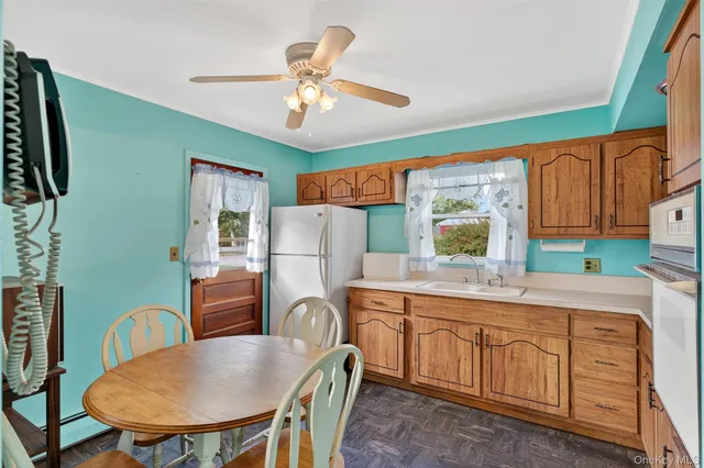 a view of a dining room with furniture a kitchen and a chandelier fan