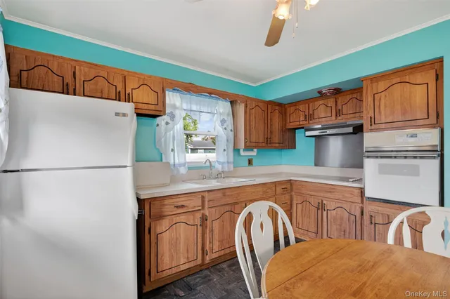 a kitchen with stainless steel appliances granite countertop a refrigerator a sink dishwasher a dining table and chairs with wooden cabinets