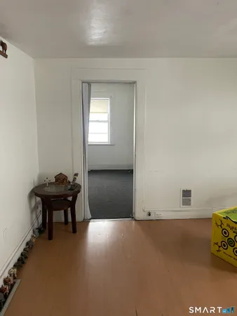 a view of a hallway with wooden floor and a livingroom