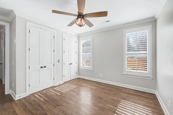 an empty room with wooden floor and ceiling fan