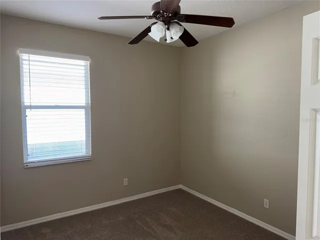an empty room with a window and a fan