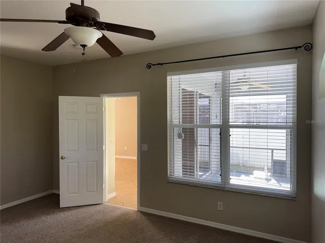 a view of empty room with window and ceiling fan