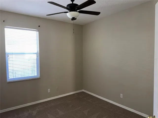 an empty room with a window and a fan