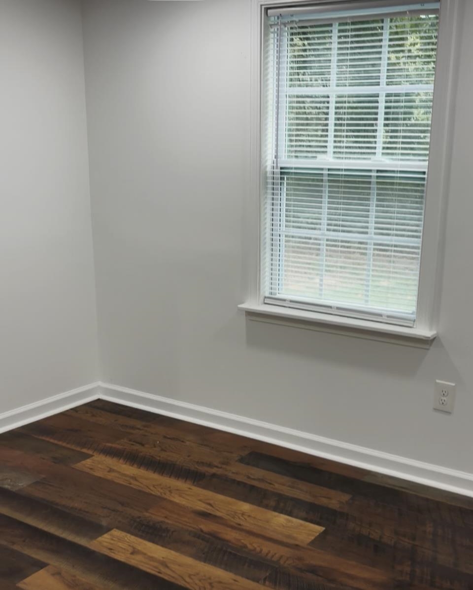 4769 West Union Road Millington, TN 38053 - Photo 8 of 12 White walls with contrasting wood-finish flooring, featuring a double-hung window with white trim and blinds