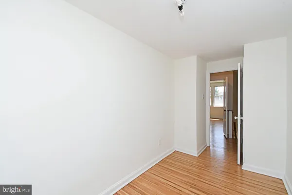 a view of an empty room with wooden floor and closet