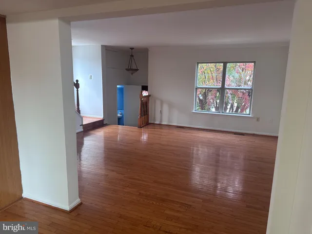 a view of a hallway with wooden floor and a living room