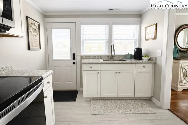 a kitchen with granite countertop a sink cabinets stainless steel appliances and a window