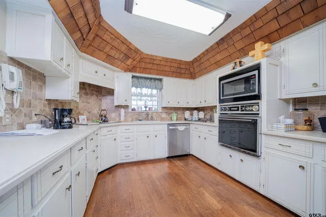 a kitchen with granite countertop white cabinets and white appliances