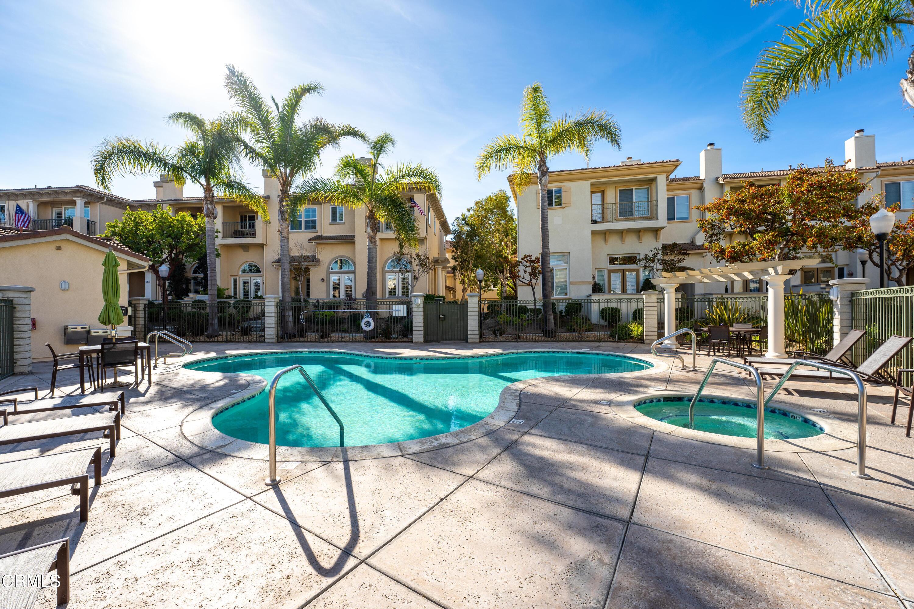 1239 Bayside Lane Oxnard, CA 93035 - Photo 24 of 27 a view of a white house with a yard and table and chairs under an umbrella