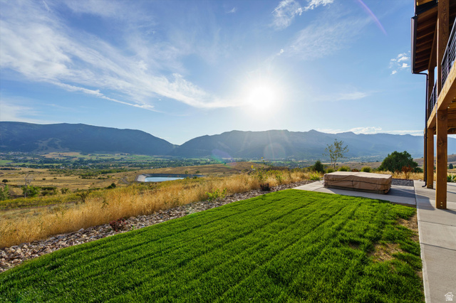 4499 North Seven Bridges Road, Unit 9 Eden, UT 84310 - Photo 51 of 65 Expansive mountain backdrop, manicured lawn, concrete patio, and upper-level balcony with metal railing