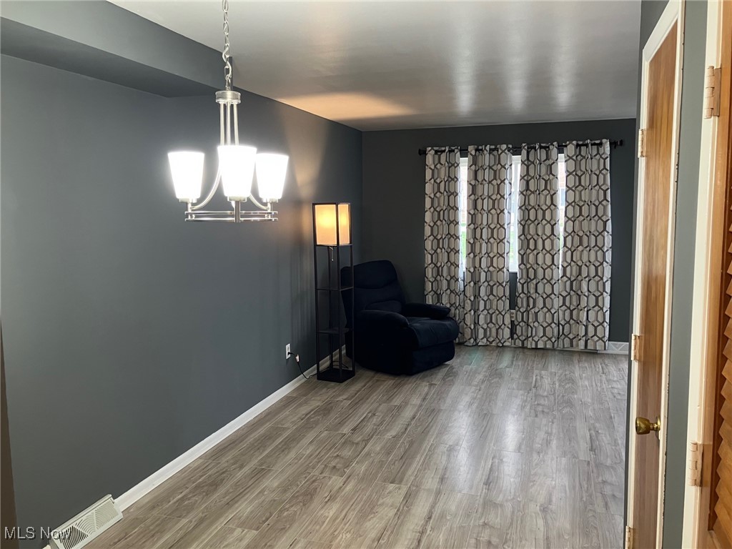797 Babbitt Road, Unit 9 Euclid, OH 44123 - Photo 8 of 10 Living area featuring visible vents, baseboards, a chandelier, and wood finished floors