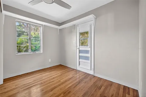 a view of an empty room with window and wooden floor