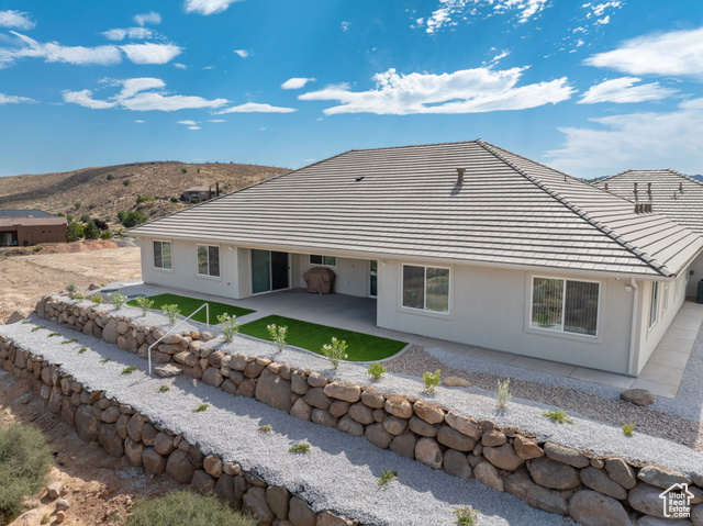 230 Boulder Way Leeds, UT 84746 - Photo 52 of 72 Rear view of house with a covered patio, step down terraced low-water landscaping and stucco siding with stone retaining walls and step down ladders. Concrete sidewalks surround the home.