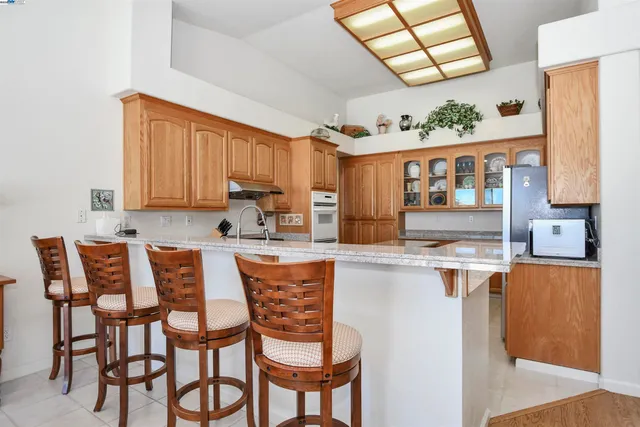 a kitchen with stainless steel appliances granite countertop a table chairs sink and cabinets